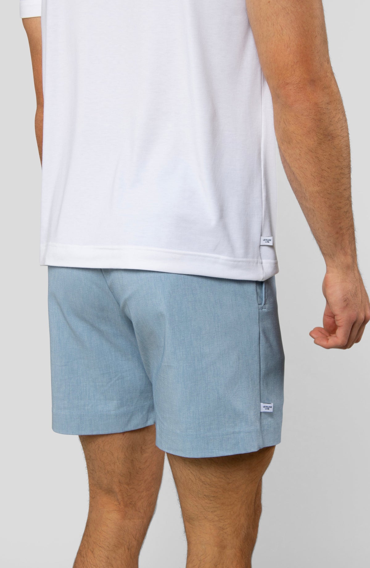 LEISURE LAB® Dockside Short in light blue technical fabric with a back view on a model wearing a white t-shirt